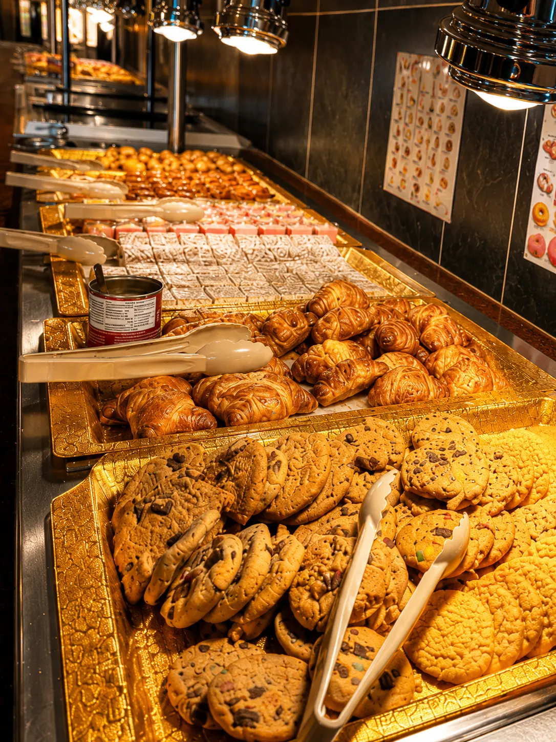 Trays of chocolate chip cookies and croissants under the lights of the dessert bar