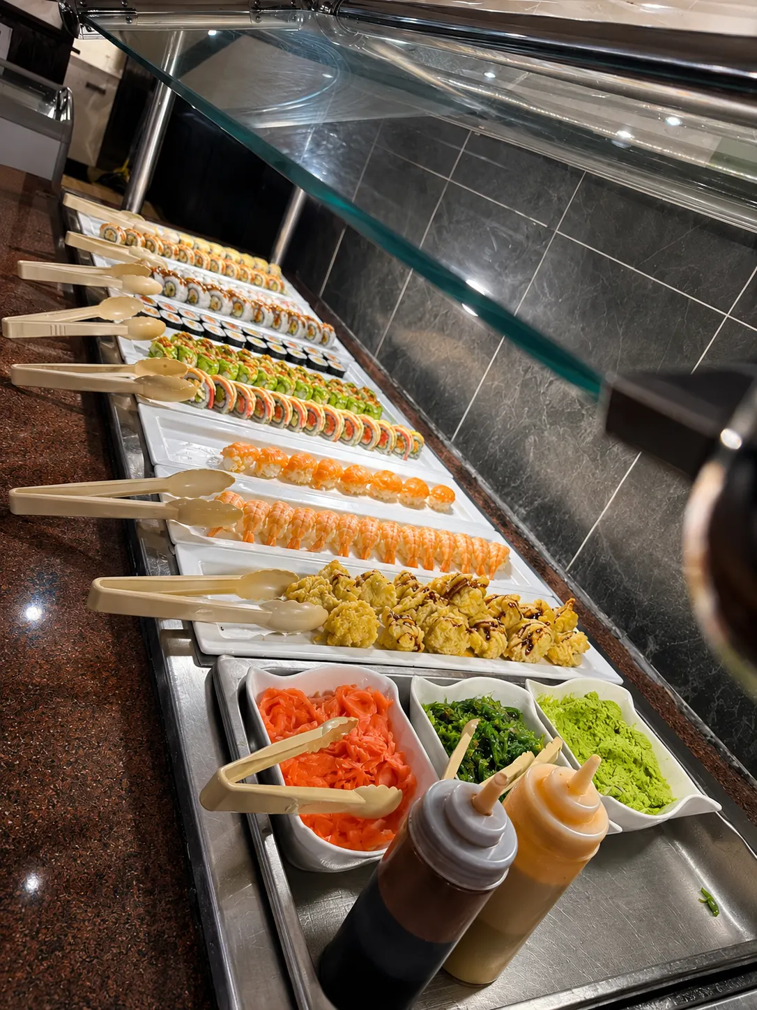Sushi bar with fresh rolls, pickled ginger, seaweed salad, and wasabi at Best Buffet & Grill